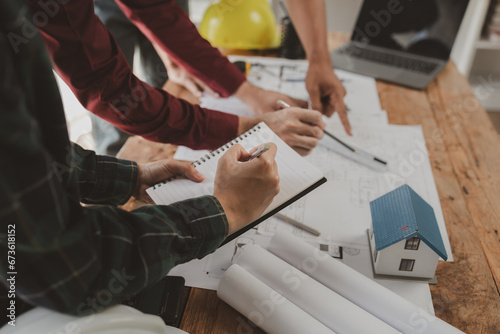 Architects and engineers work together to come up with solutions to house building problems  The property is about to be designed by a group of engineers  Architects are reviewing plans together.