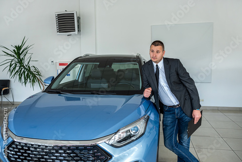  young  salesman in suit waiting for customer at the dealership. purchase car concept