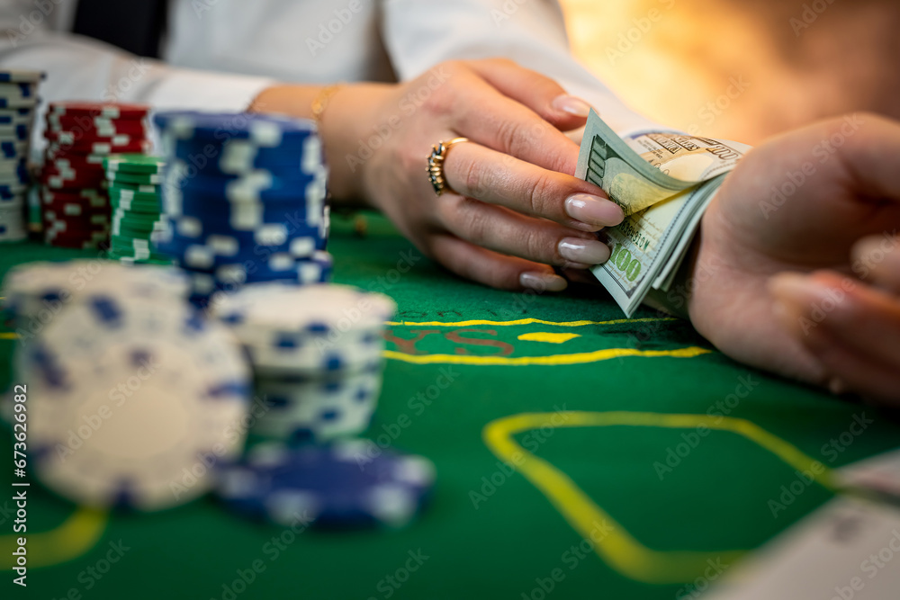 Obraz premium beautiful female player counts chips during poker in casino.