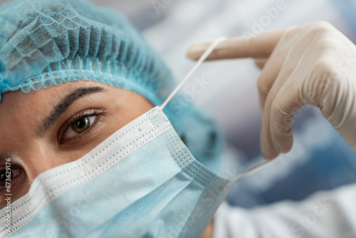 close up of caucasian young nurse or doctor takes off her protective mask after hard work at clinic
