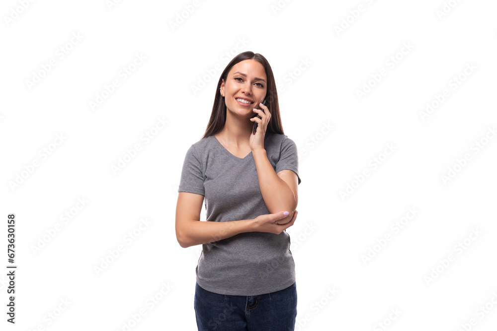 young caucasian woman with dark hair dressed in a casual gray t-shirt chatting on the phone young caucasian woman with dark hair dressed in a casual gray t-shirt chatting on the phone