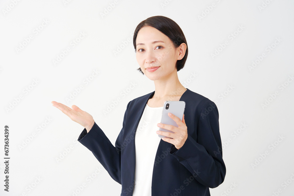 スマートフォンを持って手のひらで左側を指す中年のビジネスウーマン　白背景