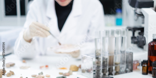 Blurred background of geologist or archaeologist is selecting sample of rock, stone or mineral in paleontology, archaeological and geological or mining laboratory. Concept of ground fossil research.