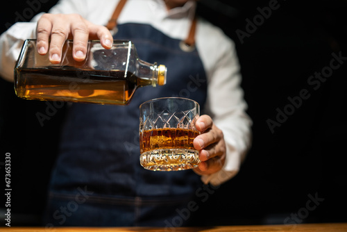 Barman pouring whiskey whiskey glass..