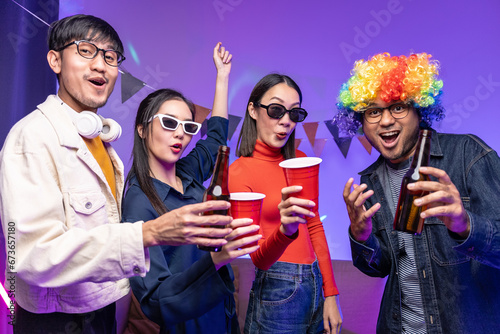 Happy asian diverse group friends celebrating with beer bottles and clinking on party. Home party friends having fun enjoying time and dancing together. New Year's Eve Party concept