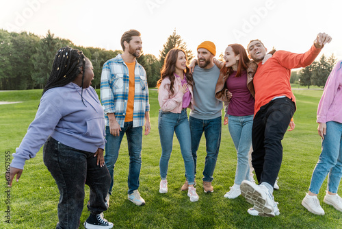 Group of multiracial smiling friends hugging, meeting at team building outdoors, talking, having fun