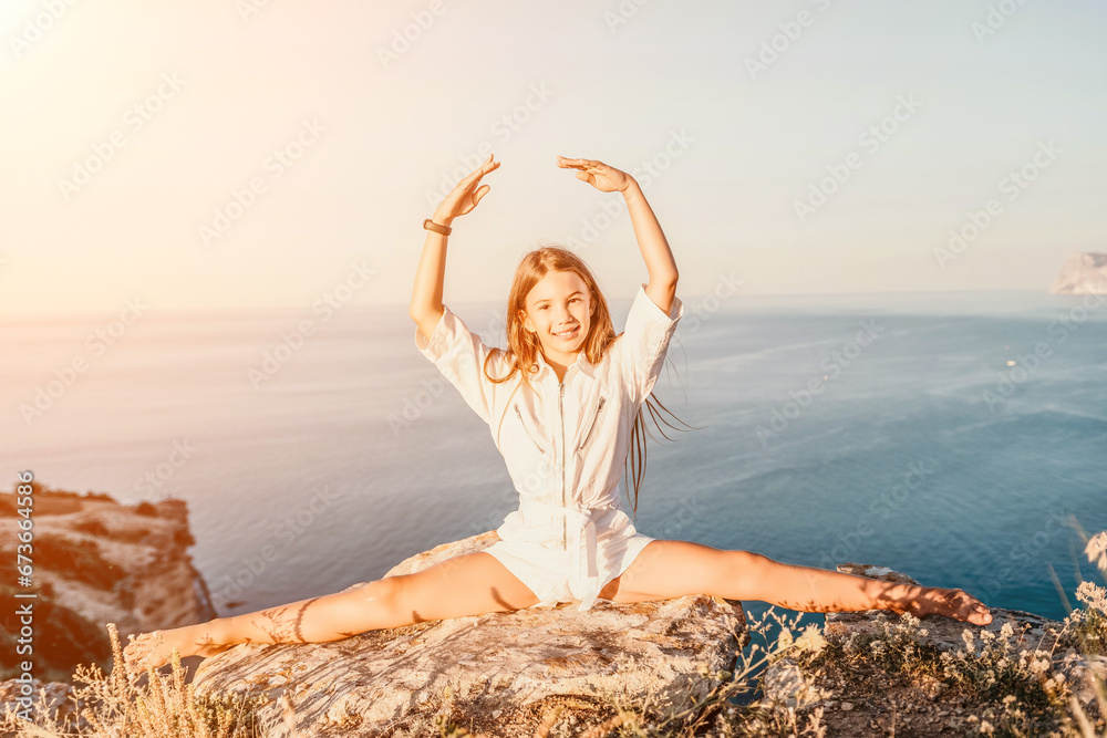 Happy smiling teen girl balerina performs stretching exercises splits on the beach during a beautiful sunset, enjoying a sunny summer day. Happy smiling teen girl balerina performs stretching exercises splits on the beach during a beautiful sunset, enjoying a sunny summer day.