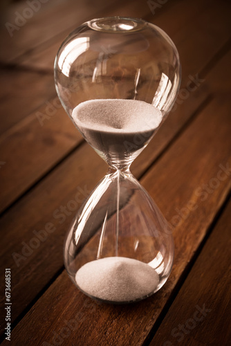 Hourglass containing white sand on a rustic wooden board