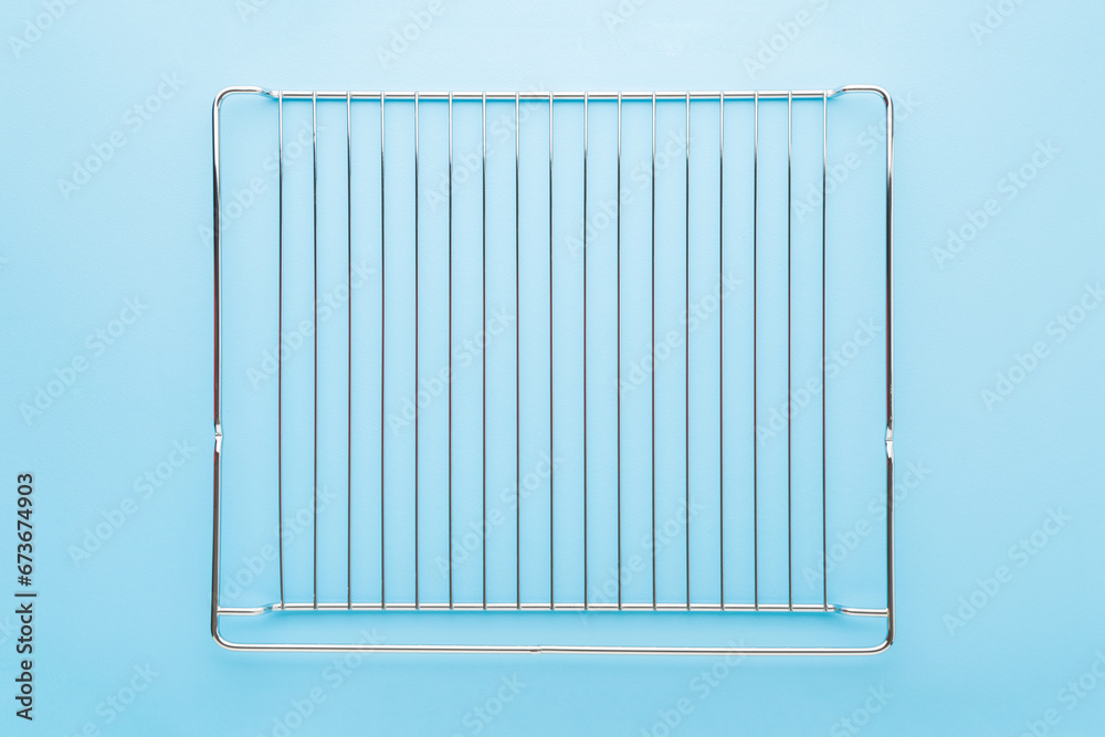 New clean steel grill grate for kitchen oven on light blue table background. Pastel color. Closeup. Top down view. New clean steel grill grate for kitchen oven on light blue table background. Pastel color. Closeup. Top down view.