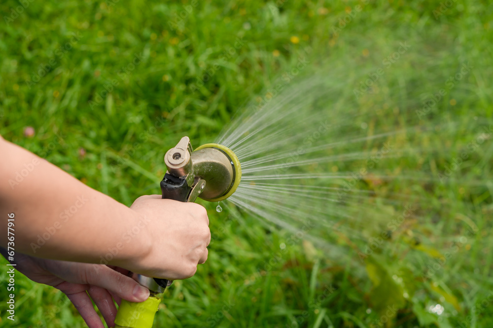 Fototapeta premium Ogrodnik podlewa trawnik przed domem 