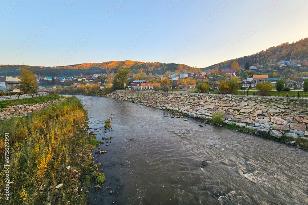 The Mayma River. Evening village on the banks of a mountain river. Rustic landscape.  Rocky bed of the river flowing through the village. Gorno-Altaisk.
