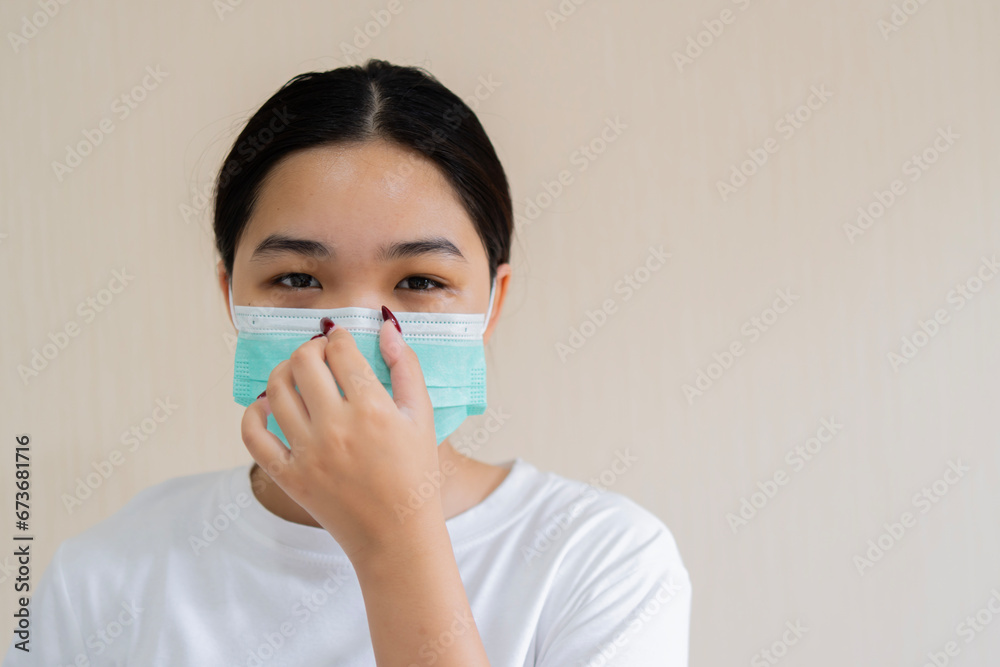 Portrait of a young girl in a medical mask and adjusting her mask isolated on a light beige wall background. Portrait of a young girl in a medical mask and adjusting her mask isolated on a light beige wall background.
