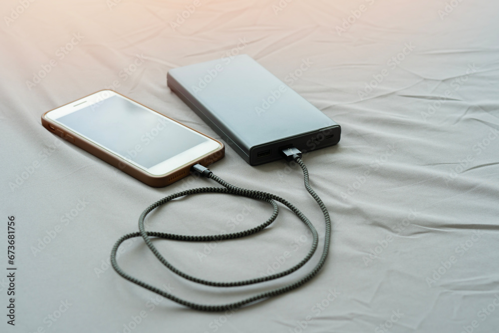Smartphone charging with pink power bank on bed in the morning with sunlight, Smartphone charging with pink power bank on bed in the morning with sunlight,