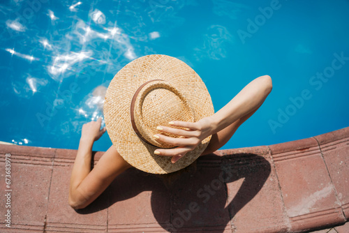 Woman wearing straw hat relaxing in pool on sunny day photo