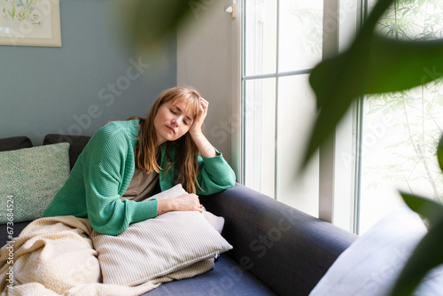 Sad woman with head in hands sitting on sofa at home photo