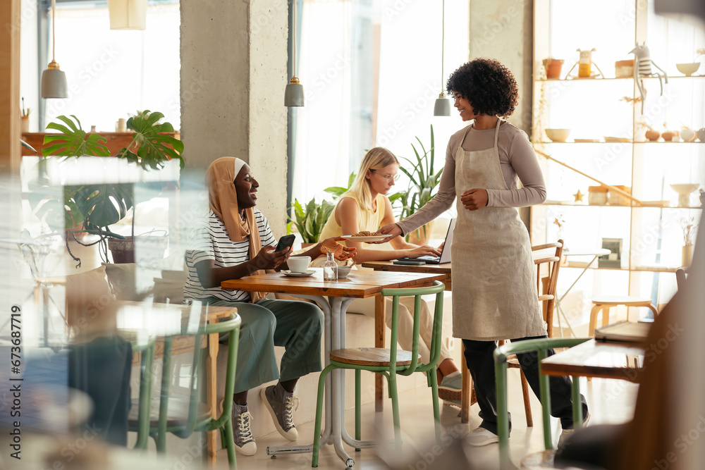 Smiling waitress serving food to customers in cafe