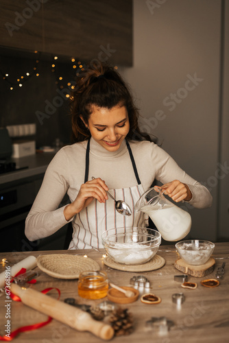 Happy caucasian carly woman cooking during winter holidays in cozy home kitchen, beautiful lady make traditional christmas gingerbread cookies on xmas day