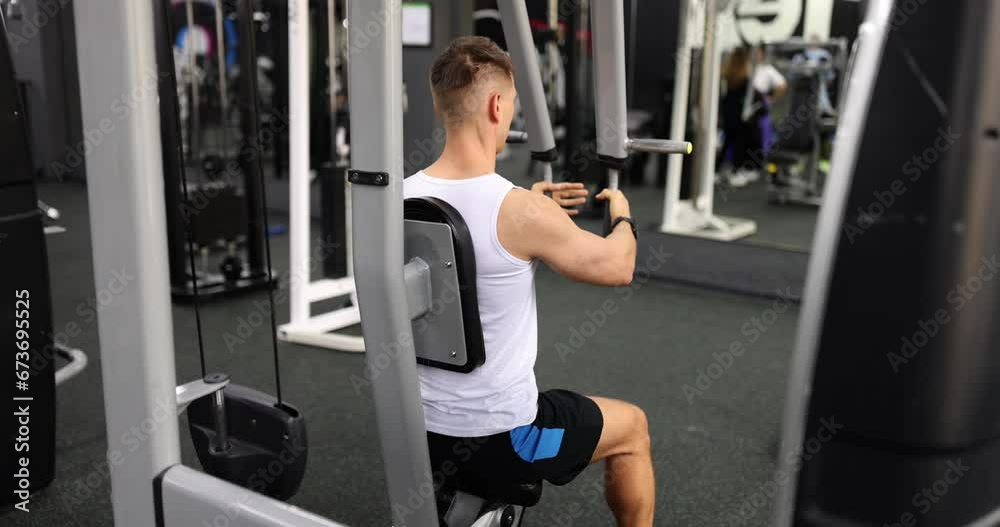 Sporty man pumps up arm muscles on professional exercise machine in sports club. Equipped gym for sports. Improved physical health and body shape slow motion Sporty man pumps up arm muscles on professional exercise machine in sports club. Equipped gym for sports. Improved physical health and body shape slow motion