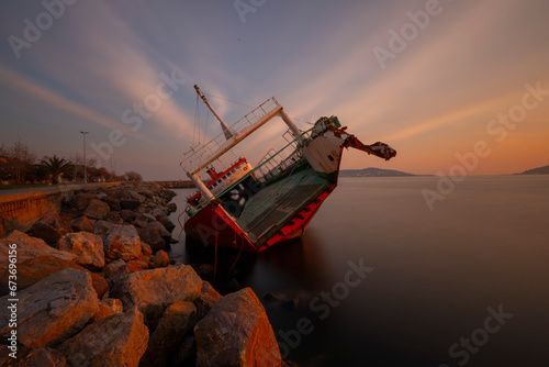 Sunken ship washed up on the seaside, sunset. photo