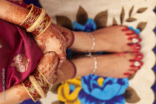 Indian Bengali Wedding Concept. Beautiful feet of an Indian bride, decorated with auspicious red color (Alta), anklets, and toe rings.