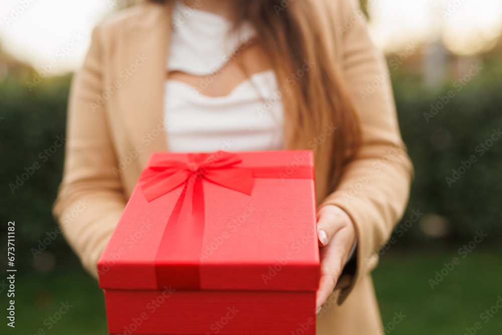 Portrait of charming lady in beige classic coat holding present box in autumn park at sunset. Portrait of charming lady in beige classic coat holding present box in autumn park at sunset.