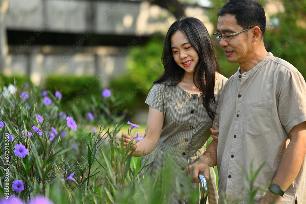 Shot of happy middle age man with a cane admiring view of plants and wild flowers with his adult daughter Shot of happy middle age man with a cane admiring view of plants and wild flowers with his adult daughter