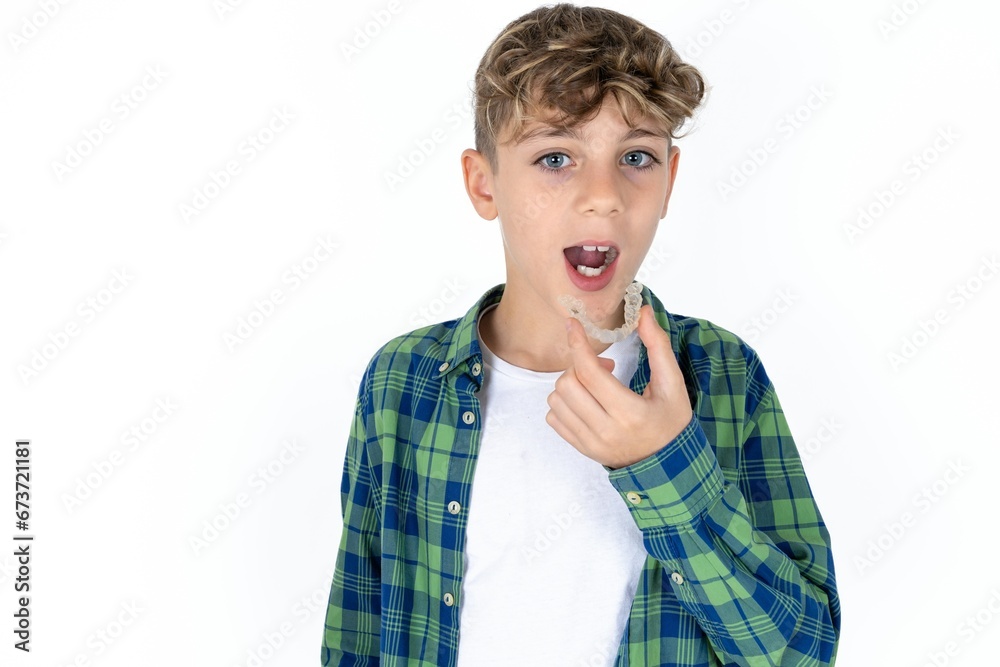 caucasian kid boy wearing plaid shirt holding an invisible aligner ready to use it. Dental healthcare and confidence concept. caucasian kid boy wearing plaid shirt holding an invisible aligner ready to use it. Dental healthcare and confidence concept.