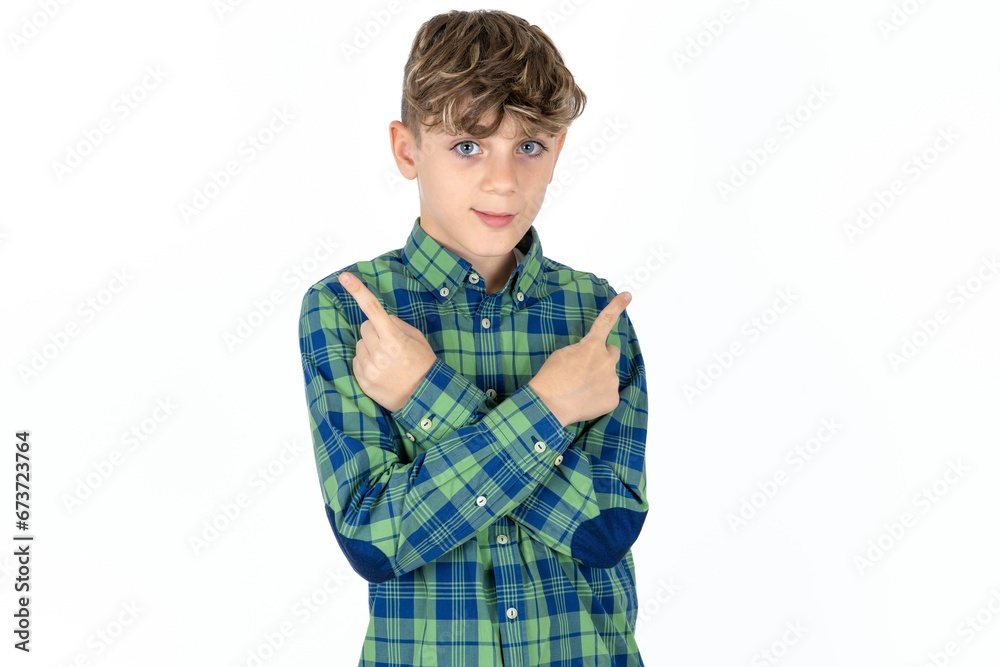Serious caucasian kid boy wearing plaid shirt crosses hands and points at different sides hesitates between two items. Hard decision concept Serious caucasian kid boy wearing plaid shirt crosses hands and points at different sides hesitates between two items. Hard decision concept