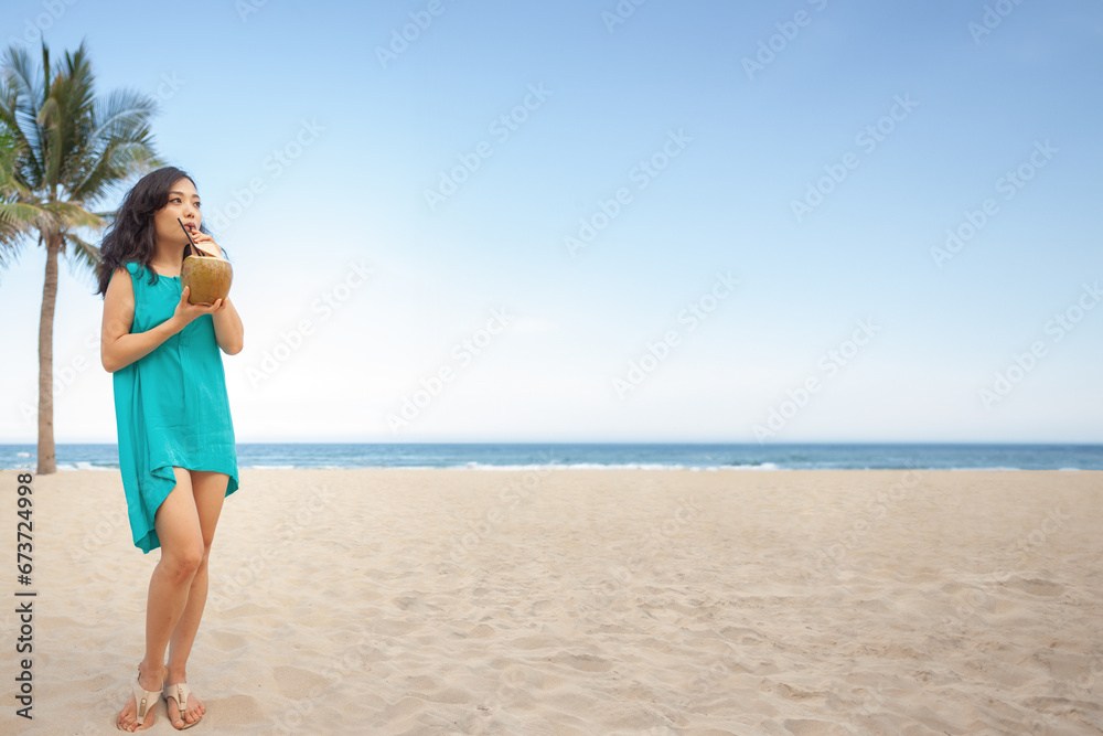 Happy Asian girl drinking fresh coconut water juice on the beach at her vacation. Tropical travel Happy Asian girl drinking fresh coconut water juice on the beach at her vacation. Tropical travel