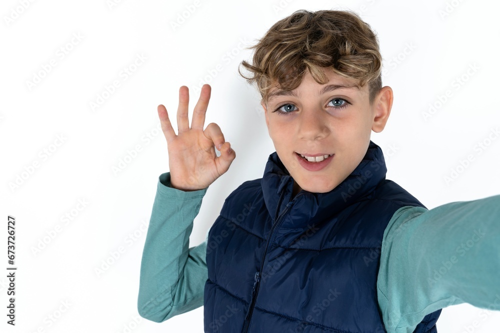 Portrait of pretty cheerful caucasian kid boy wearing blue vest make selfie show okey symbol Portrait of pretty cheerful caucasian kid boy wearing blue vest make selfie show okey symbol