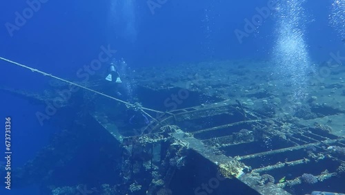 Group of scuba divers swimming on the rusty shipwreck. Remains of the ship underwater, with scuba tourist. Video from dive, seascape with wreck and people. photo