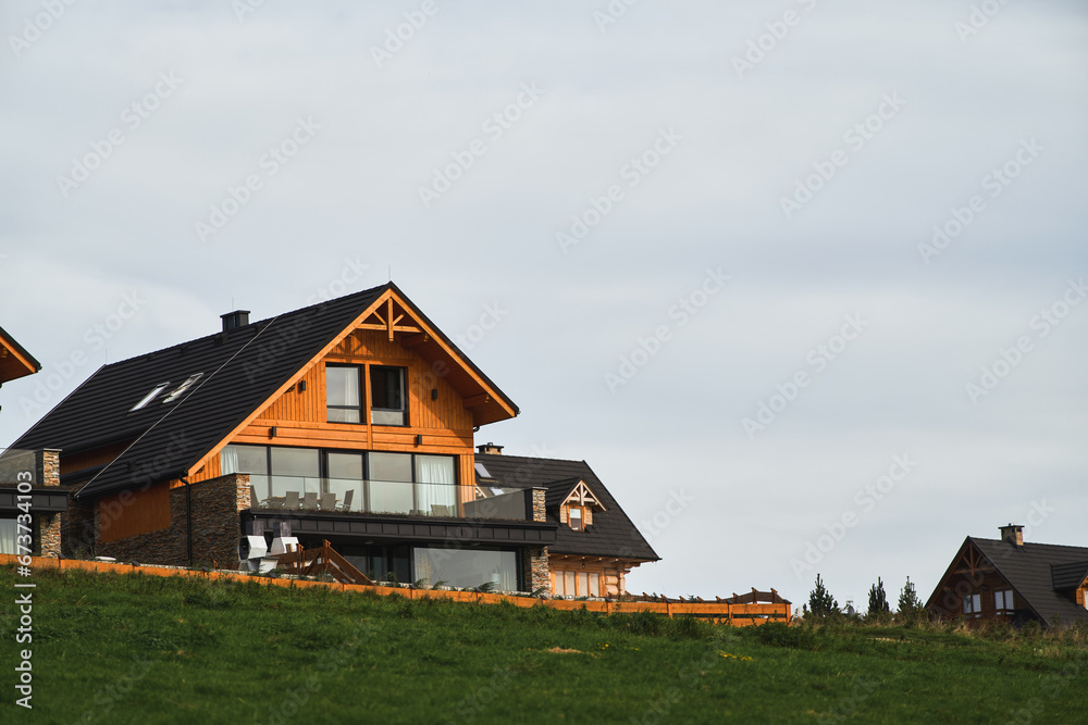 Barnhouse style houses. A street with cozy small houses. Living in the suburban. Concept of mortgage loan. Modern construction. Pros and cons of wooden house and suburban real estate concept. Barnhouse style houses. A street with cozy small houses. Living in the suburban. Concept of mortgage loan. Modern construction. Pros and cons of wooden house and suburban real estate concept.