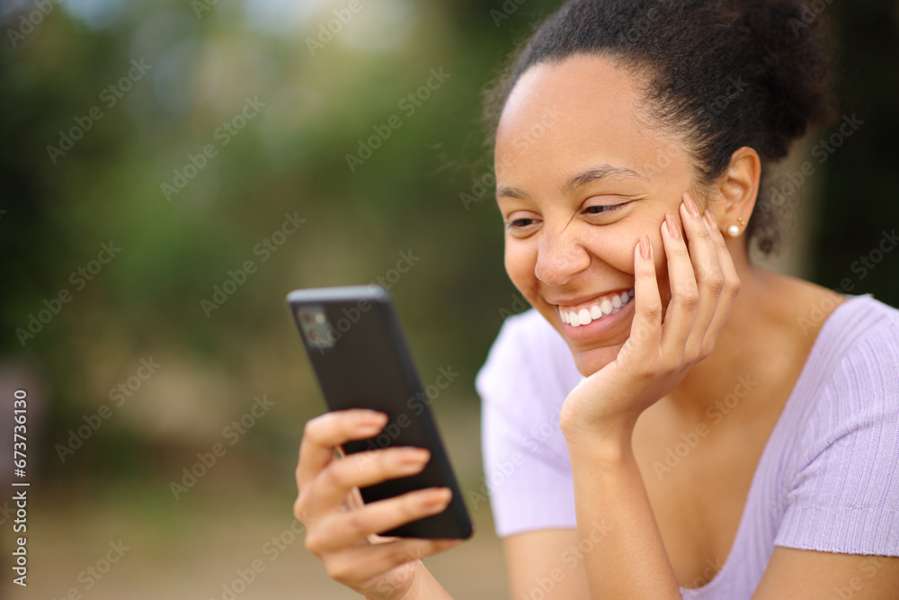 Happy black woman reading message on phone