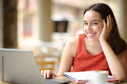 Happy student with notebook and laptop looks at you