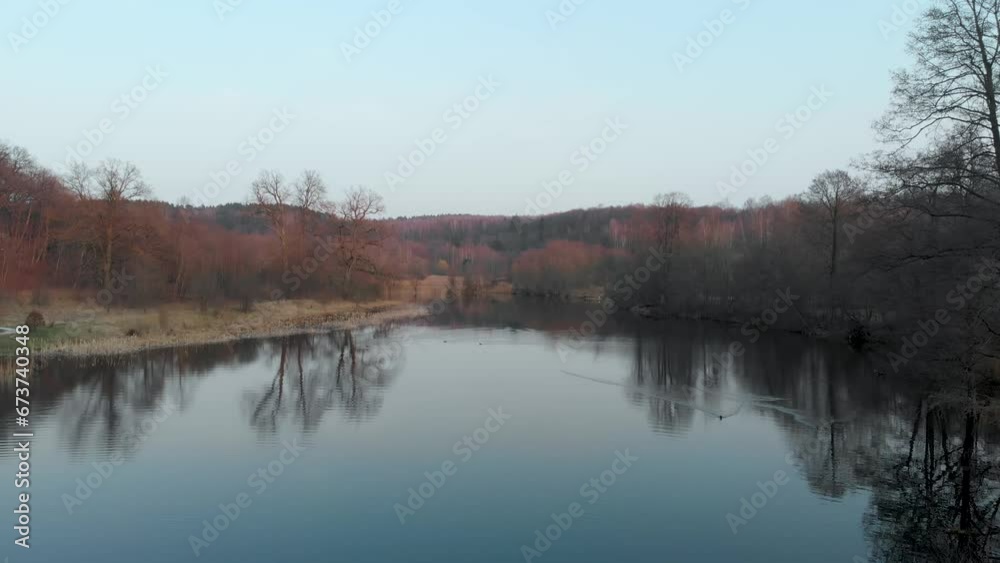 Aerial autumn view of a lake surrounded by a forest. Colorful forest scene with orange and red foliage. Aerial autumn view of a lake surrounded by a forest. Colorful forest scene with orange and red foliage.