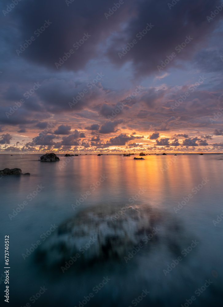 Beautiful scenery. sea sunset on the sea. Stones in the sea, a large stone is visible through the water column. Dramatic clouds and dark sky. Sunset in Phuket, Khaolak, Thailand.