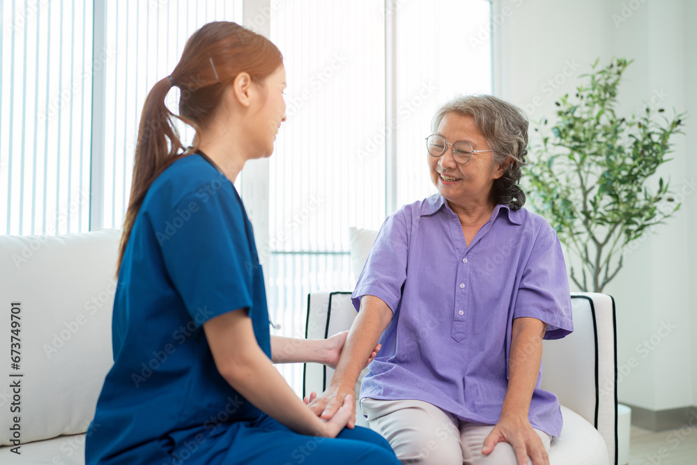 Obraz premium Asian young nurse taking care and talking mature female patient sitting on sofa in hospital. Healthcare concept.