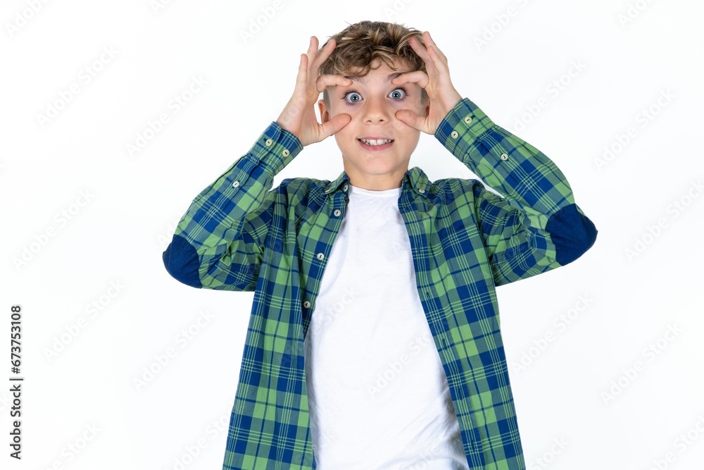 Caucasian teen boy wearing green plaid shirt over white background keeping eyes opened to find a success opportunity. Caucasian teen boy wearing green plaid shirt over white background keeping eyes opened to find a success opportunity.