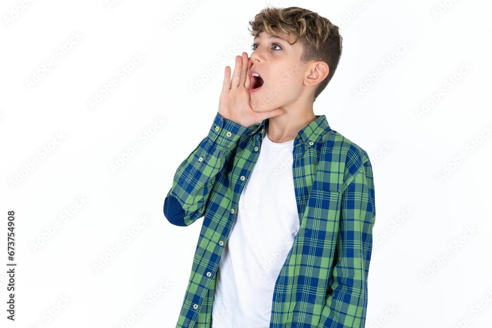 Caucasian teen boy shouting and screaming loud to side with hand on mouth. Communication concept. Caucasian teen boy shouting and screaming loud to side with hand on mouth. Communication concept.