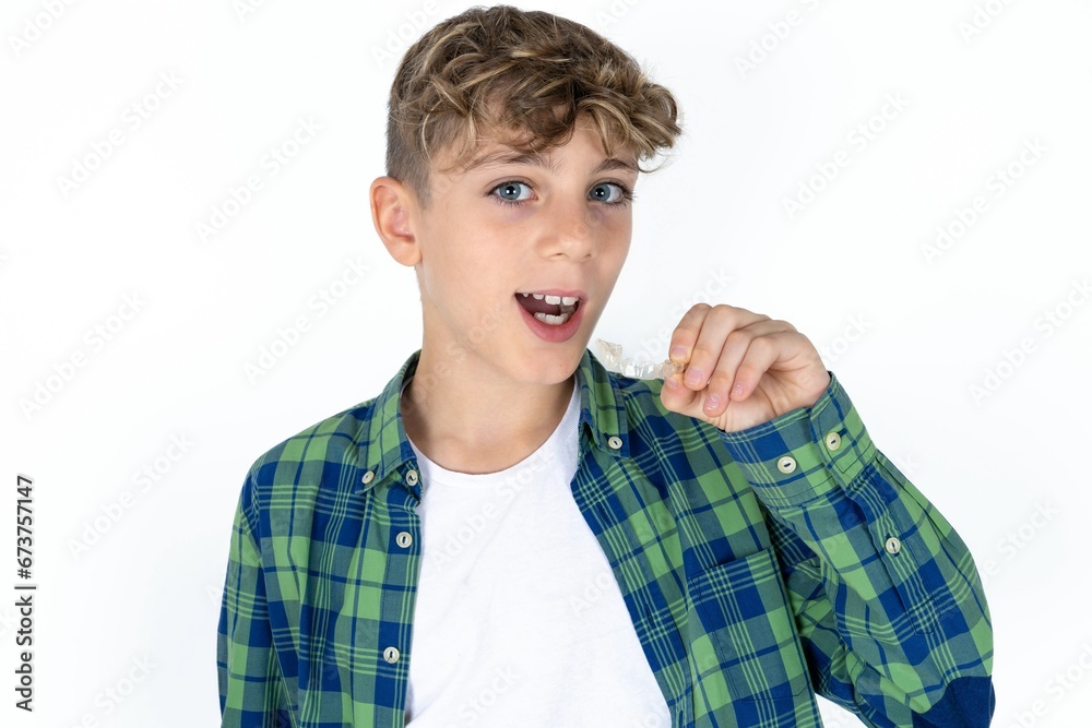 Caucasian teen boy holding an invisible braces aligner and rising thumb up, recommending this new treatment. Dental healthcare concept. Caucasian teen boy holding an invisible braces aligner and rising thumb up, recommending this new treatment. Dental healthcare concept.