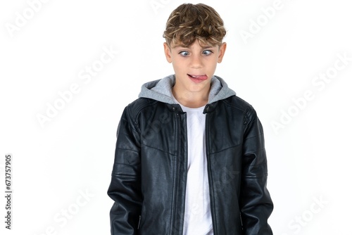 Funny Caucasian teen boy makes grimace and crosses eyes plays fool has fun alone sticks out tongue. photo