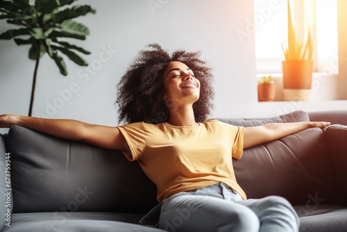 happy young african american woman relaxing and lying on the sofa at home photo