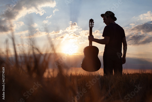 silhouette of man with guitar and hat, summer music festival