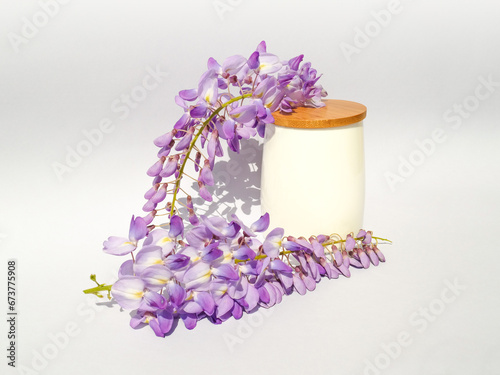 White bamboo cup with wisteria flowers on gradient white and gray background. Natural minimal concept. Creative spring idea. Wisteria decoration.