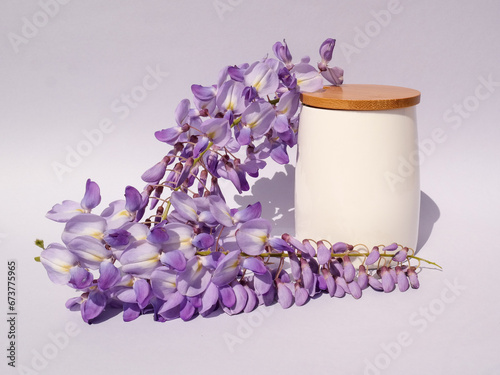 White bamboo cup with wisteria flowers on gradient white and gray background. Natural minimal concept. Creative spring idea. Wisteria decoration.