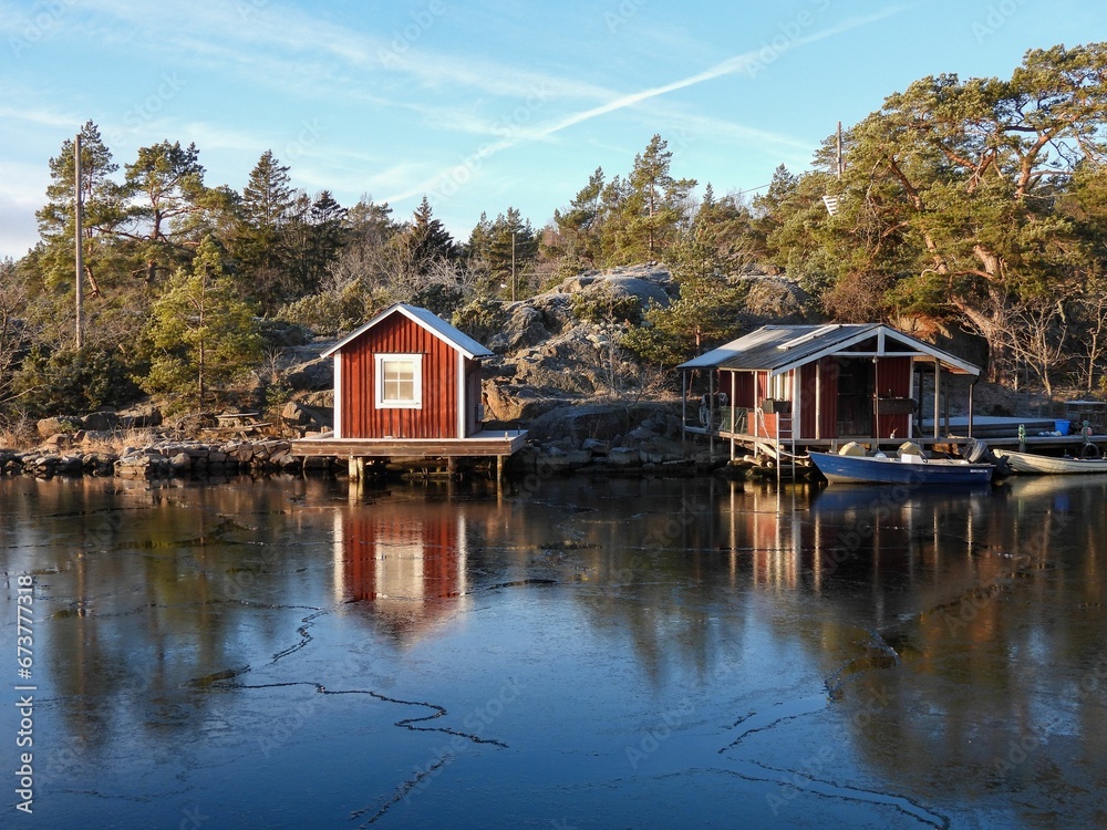 Picturesque cabins and a boat on the shore of a tranquil lake with trees in the background
