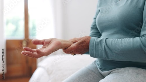 Hand, wrist pain or arthritis with a senior on the bed in a home for recovery from injury closeup. Anatomy, osteoporosis or fibromyalgia with an elderly person in the bedroom of an apartment photo