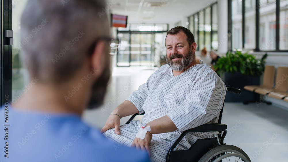 Close up of supportive doctor talking with worried overweight patient in wheelchair. Illnesses