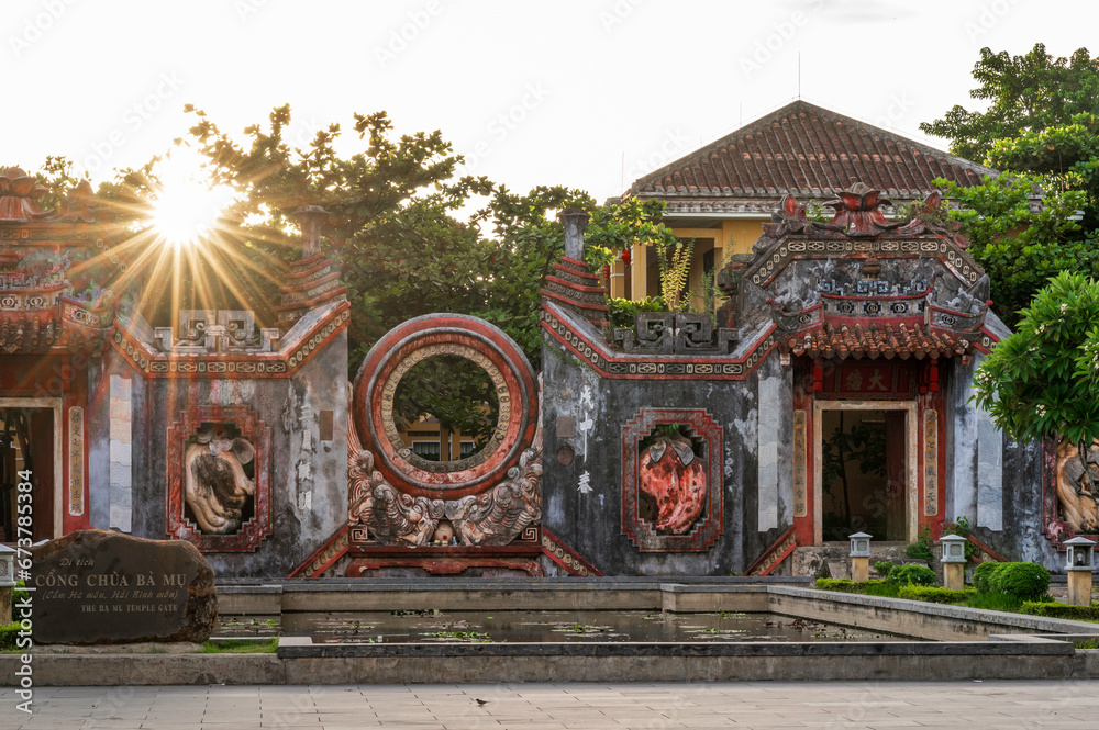 sunrise at the Bà Mụ Temple, Hoian, Vietnam. The sun is shining through a gap in the temple's facade