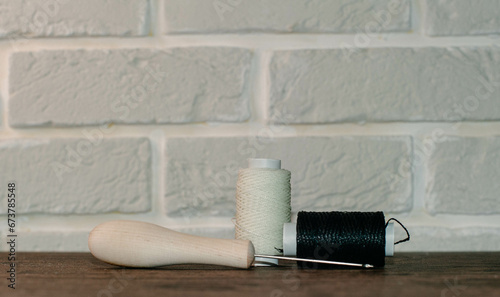 Cuadro en lienzo Shoe awl and skeins with white and black threads.